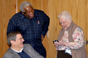 two men looking at woman on her phone