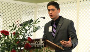 male student in suit at podium