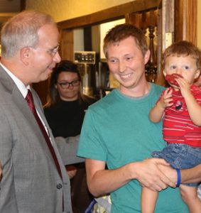 man holding his son talking to another man